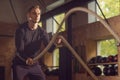 Fit, sporty and athletic sportsman working in a gym. Man training using battle ropes. Sports, athletics and fitness