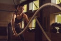 Fit, sporty and athletic sportswoman working in a gym. Woman training using battle ropes. Sports, athletics and fitness