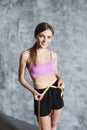 Fit and sporty girl measuring her perfect body on gray stylish background. Royalty Free Stock Photo