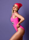 Fit and sporty girl posing in pink swimsuit and red hat over pink background Royalty Free Stock Photo