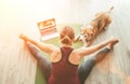 Fit sporty healthy woman sit on mat in Upavistha Konasana pose, doing breathing exercises, watching online yoga class on laptop