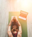 Fit sporty healthy woman sitting on mat in Paschimottanasana pose, doing breathing exercises, watching online yoga class on laptop Royalty Free Stock Photo