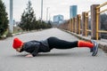 Fit sporty middle aged blonde 40s woman in red cap Standing in Plank, doing workout, stretching, enjoying fitness at