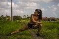 Fit and sporty runner Asian woman stretching leg and body after running workout on green field beautiful background in sport train Royalty Free Stock Photo