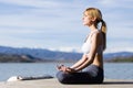 Fit and sporty young woman doing yoga next to the lake. Royalty Free Stock Photo