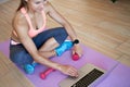 Fit sporty young woman sit on mat using laptop fitness training online at home. Royalty Free Stock Photo