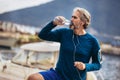 Fit thirsty senior man drinking water before running.