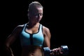 Fit woman concentrating while lifting dumbbell