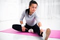 Fit woman doing aerobics gymnastics stretching exercises her leg and back to warm up at home on yoga mat. Royalty Free Stock Photo