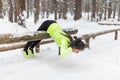 Fit woman doing back extension exercise outdoors in woods. Female sports model exercising outdoor winter park