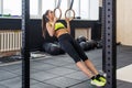 Fit woman doing pull-ups with gymnastic rings in gym, young female working out biceps, triceps, abs Royalty Free Stock Photo