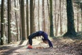 Fit woman doing yoga in forest.