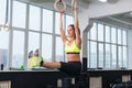 Fit woman exercising with gymnastic rings raising legs in gym. Royalty Free Stock Photo