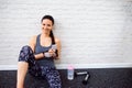 Fit woman in gym holding smart phone, brick wall Royalty Free Stock Photo