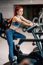 Fit active woman in the gym using gym machines, working out on stationary bicycle.  Fitness and bodybuilding concept Royalty Free Stock Photo