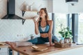 Fit woman having breakfast in split position on the kitchen table. Royalty Free Stock Photo