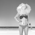 Fit woman hide behind straw hat on seashore applying sun cream