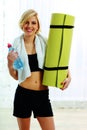 Fit woman holding a bottle with water and yoga mat Royalty Free Stock Photo