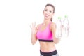 Fit woman holding water bottles and showing okay