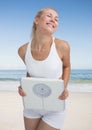 Fit woman holding a weight scale on the beach Royalty Free Stock Photo
