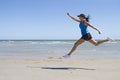 Fit woman leaping mid air on a beach Royalty Free Stock Photo