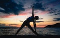 Fit woman practicing the extended triangle yoga pose on a dreamy beach