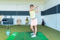 Fit woman practicing golf swing during professional class indoors Royalty Free Stock Photo