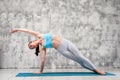 Fit woman in side plank yoga position indoors