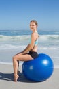 Fit woman sitting on exercise ball at the beach smiling at camera Royalty Free Stock Photo