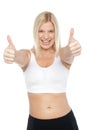 Fit woman in sports bra gesturing double thumbs up