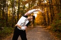 Fit woman in sportswear does side bends outdoor in autumn. Fitness, active morning, training and healthy lifestyle. Park