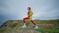 Fit woman stretching body at rugged coast. Sporty girl exercising cloudy nature