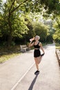 Active woman stretching and hydrating on a sunny park path Royalty Free Stock Photo