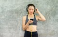 Fit women using smart phone connection internet with headphone and listening to music while sitting with relax after the training Royalty Free Stock Photo