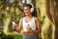 Fit woman walking in park with headphones and smartphone outdoors Royalty Free Stock Photo