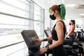 Fit women exercising on treadmill wearing face mask in gym during pandemic