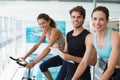 Fit women in a spin class with trainer taking notes and smiling at camera Royalty Free Stock Photo