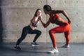 Fit woman wrestle on hands with a female opponent looking in her eyes.