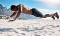 Fit young black man doing plank hold exercises on sand at the beach in the morning. African American muscular male Royalty Free Stock Photo