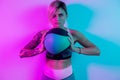 Fit young blonde woman exercise with medicine ball in gym in neon lights. Royalty Free Stock Photo