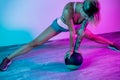 Fit young blonde woman exercise with medicine ball in gym in neon lights. Royalty Free Stock Photo