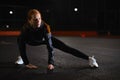 Fit young woman doing stretching workout outdoors in city street at night. Royalty Free Stock Photo