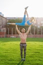 Fit young couple doing acro yoga in the park or on the field stadium. Man standing on the grass and balancing his woman on hands. Royalty Free Stock Photo