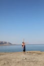 Fit young couple doing acro yoga at spa retreat on sea beach. Active woman balancing on partner feet, stretching at