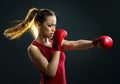 Fit, young, energetic woman boxing, black background