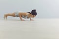 Fit young girl doing plank during her morning yoga practice, grey background. Sports instructor performing core exercise