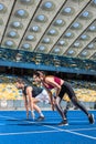 fit young male and female sprinters in start position on running track
