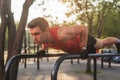 Fit young man doing push ups on horizontal bar outdoors. Royalty Free Stock Photo