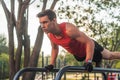 Fit young man doing push ups on horizontal bar outdoors Royalty Free Stock Photo