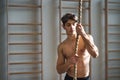 Fit young man in gym standing topless , holding climbing rope. Royalty Free Stock Photo